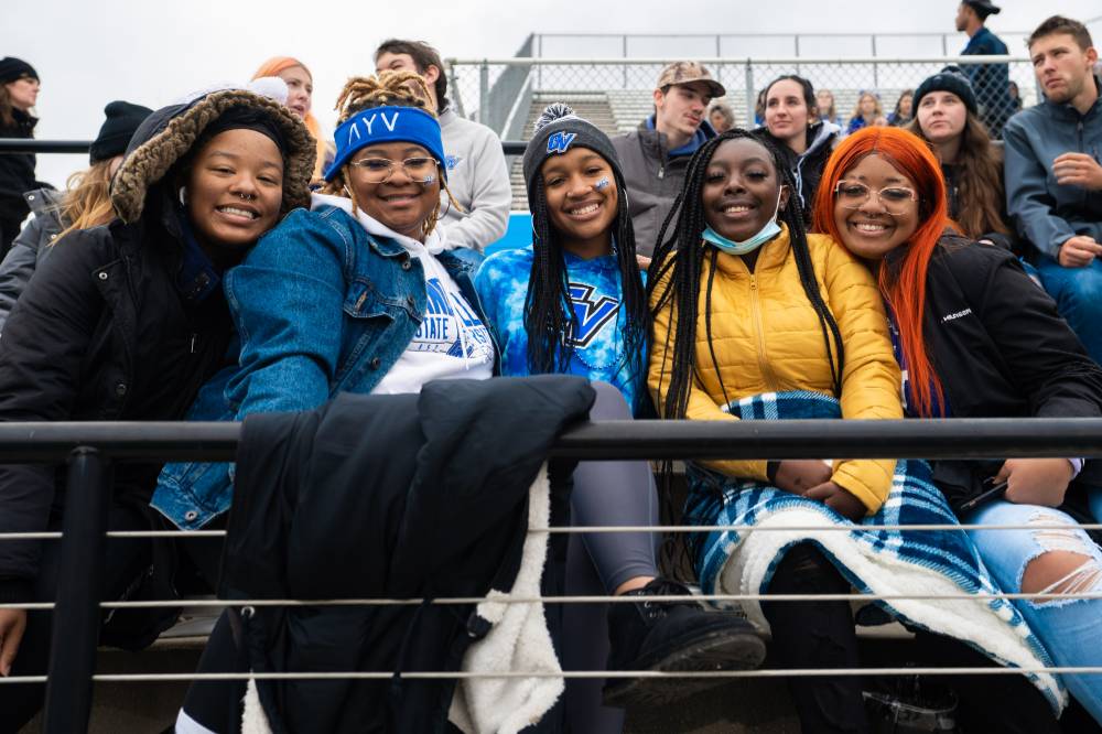 A group of students smile in the stands at Lubbers Stadium